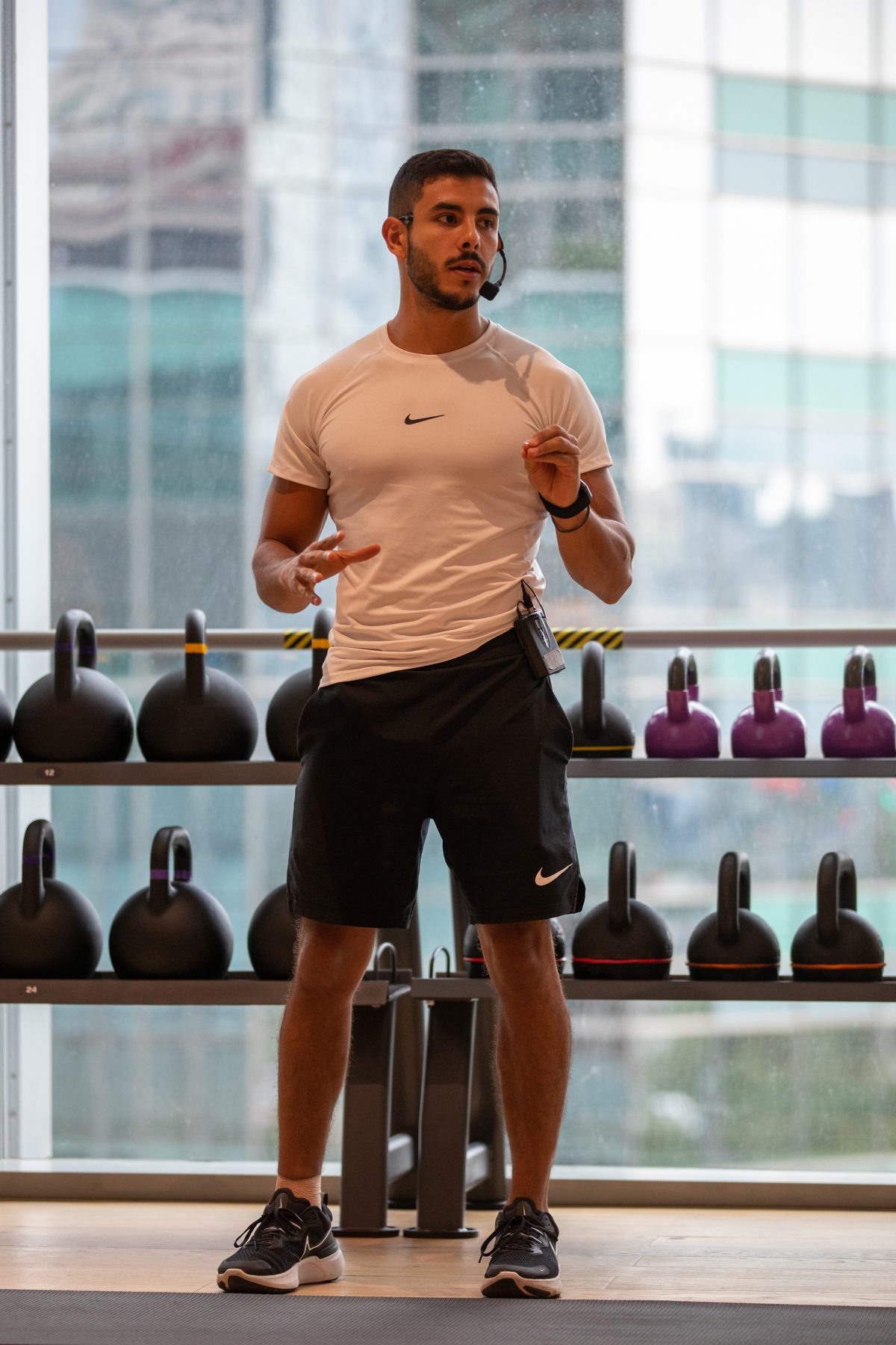 Angelo coaching a class with a headset in front of kettlebells
